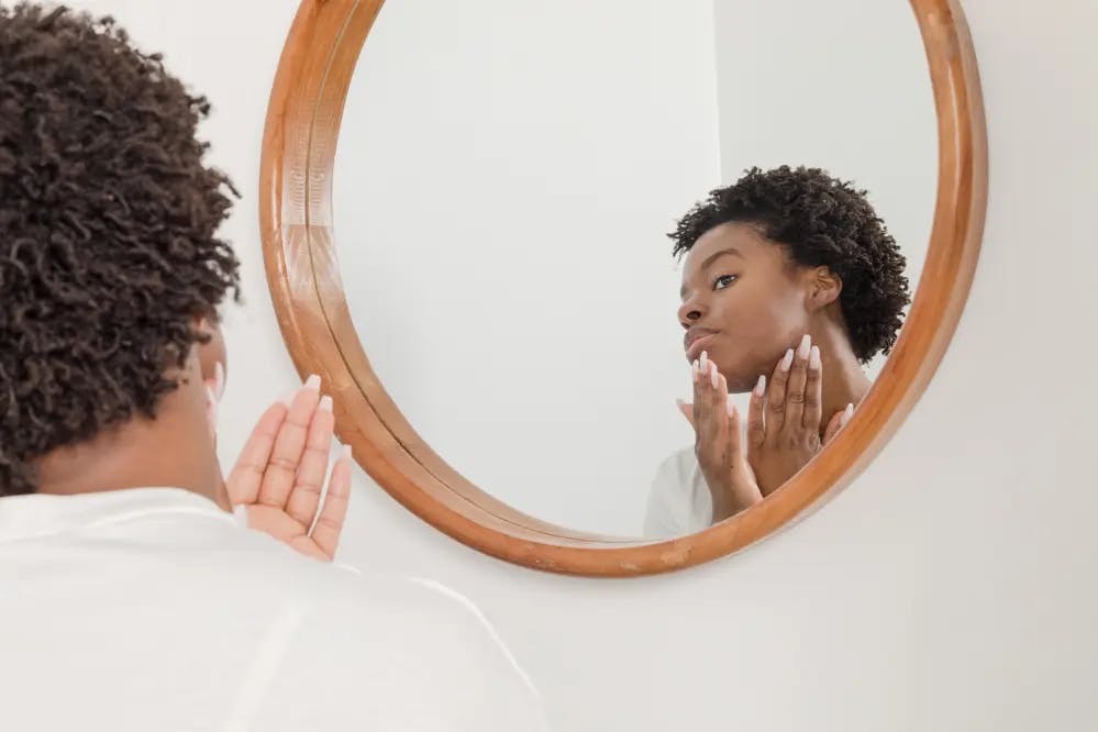 Cover Image for A woman applying product in front of a mirror