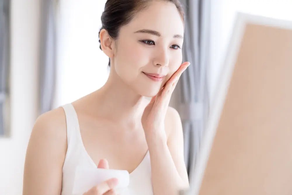 Cover Image for An asian woman with clear skin looking at her mirror