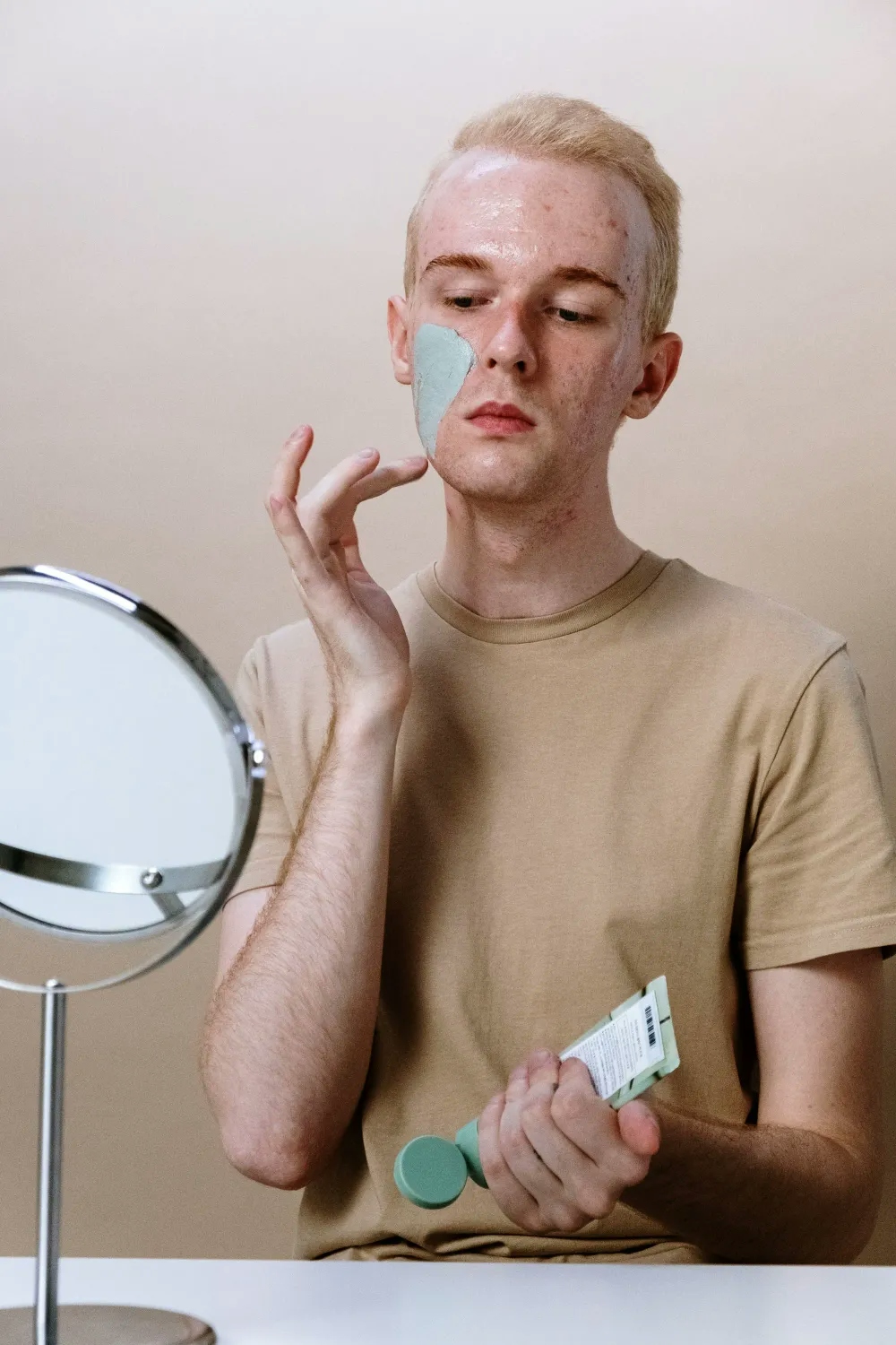 Man applying a mask pack in front of a mirror